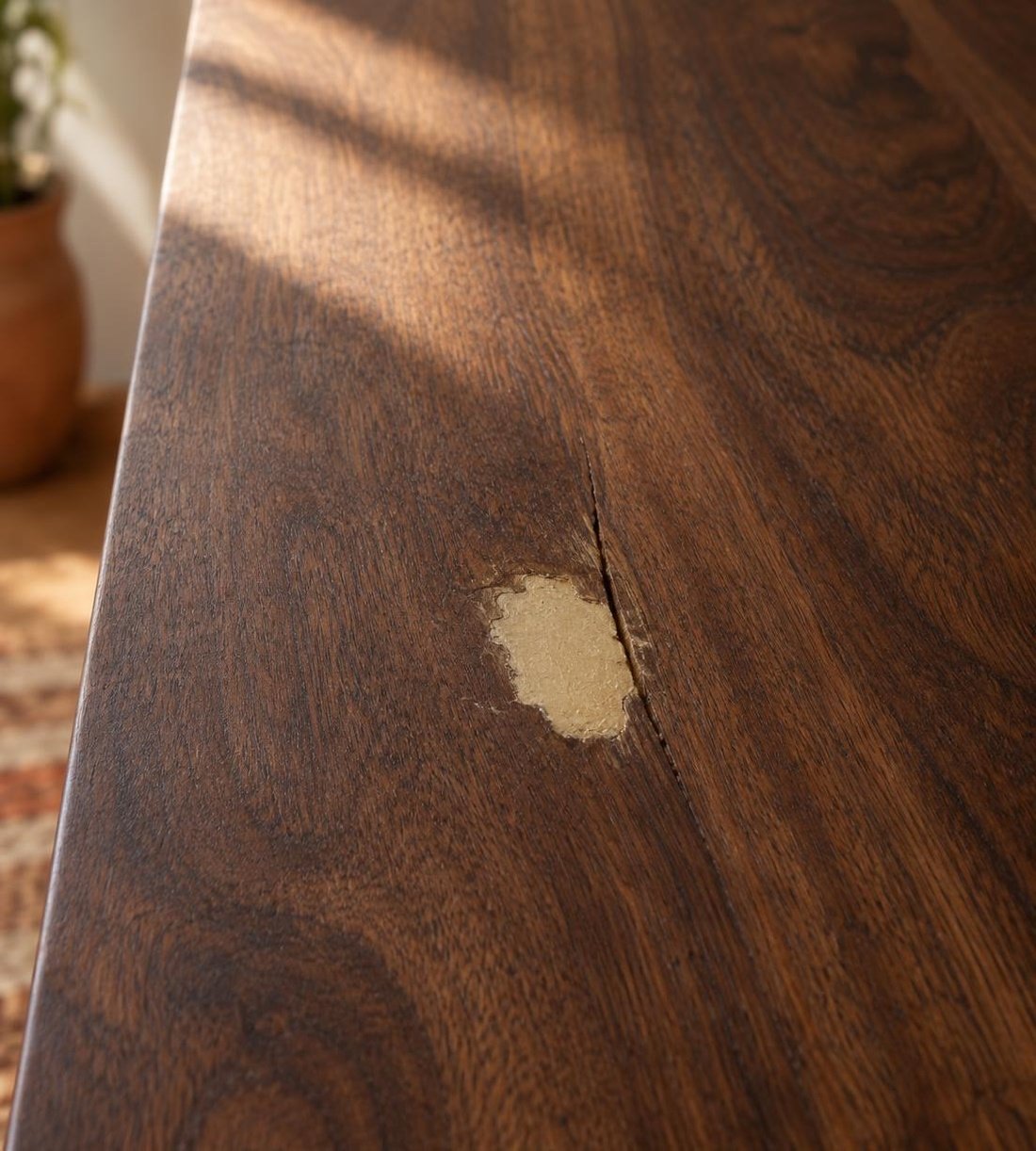 Table en noyer foncé avec un trou rebouché d'une pâte trop claire, plus visible que le défaut